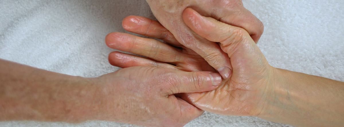 Massage van een hand, waarbij de duimen van de masseur de handpalm bewerken