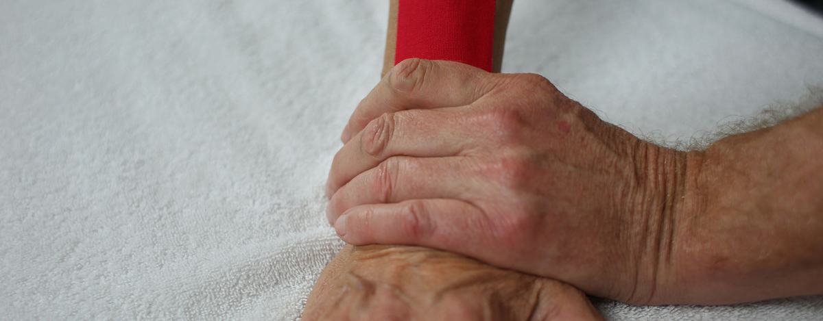 Rode elastische medical tape op een arm, aangebracht door de masseur